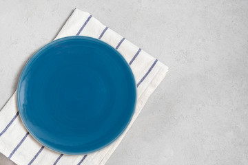 Top view of blank flat blue plate on neutral concrete table with copy space