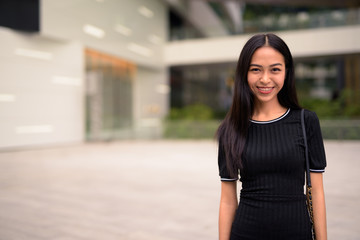 Fototapeta premium Happy young beautiful Asian tourist woman at the mall outdoors