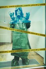 Ugly man in empty apartment behind barrier tape dressed to protective suit and mask