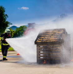 Young Firefighters practising putting out fire with fire hose.
