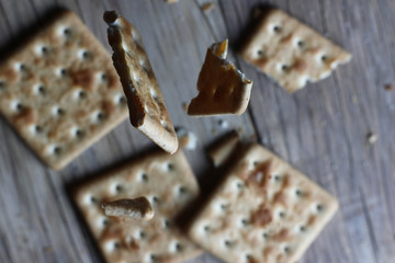 broken crackers falling on a textured table and old wood