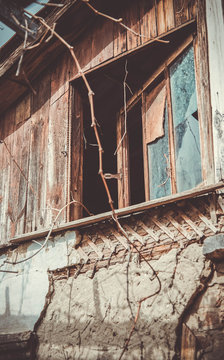 An old abandoned house with a window to the attic. peeling plaster and broken glass in the window.