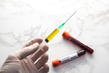 corona virus vaccine syringe on hand with blood sample