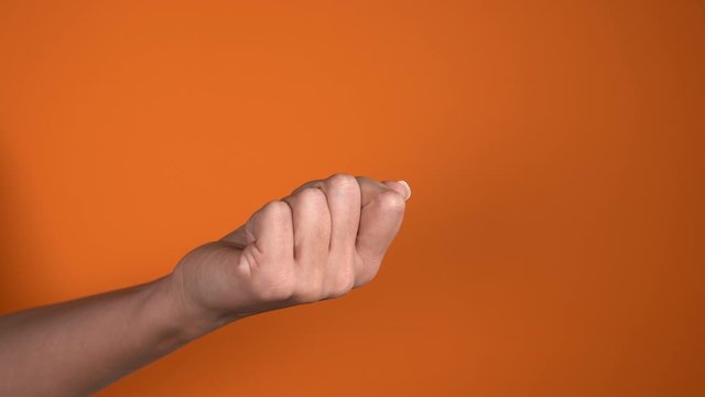 Closeup view 4k video footage of one manicured female hand isolated on bright orange background. Woman raising middle finger up as symbol of offense and contempt.