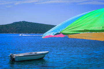 Summerday at the beach with blue sky, boat and sunshade.