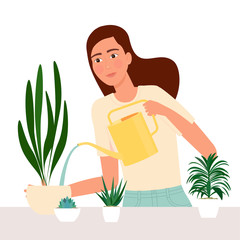 Beautiful young woman watering houseplants.