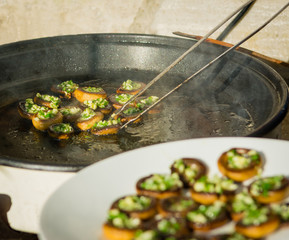 Frying button mushrooms filled with garlic and parsley on a warm autumn family picnic.