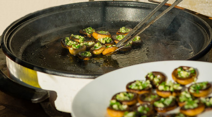 Frying button mushrooms filled with garlic and parsley on a warm autumn family picnic.