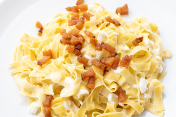 close up of fresh homemade pasta with cheese and fried bacon