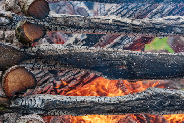 Wooden border on a meadow, which is lit as a fireplace during the holiday witch burning. Fire, smoke and hot coals can be seen.