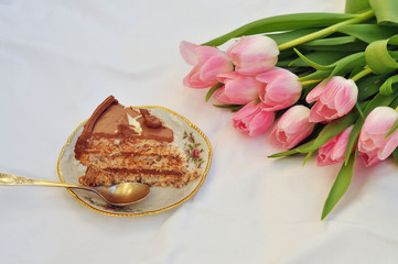 cake and bouquet of tulips on white background