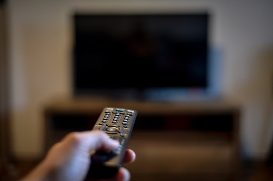 Stay At Home Concept Photo With Person Holding A Tv Remote Control Zapping The News