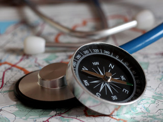 Stethoscope and compass on a map, closeup © sabdiz