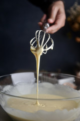 Making pancakes, cake, muffins. baking side view of baker hands pouring batter and whisking batter in bowl. Concept of cooking ingredients and method on dark background, Dessert recipes and Homemade.