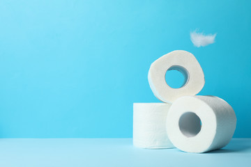 Toilet paper and feathers on blue background, space for text