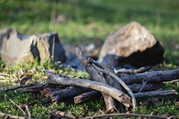 Firewood for a fire piled in a pile against a background of stones and green grass. With blurry background.