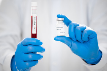 Close-up of test tube with a blood test and a coronavirus vaccine in hands of doctor. Concept of...
