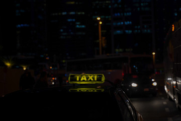 yellow taxi sign on cab car at evening or night in the city street.