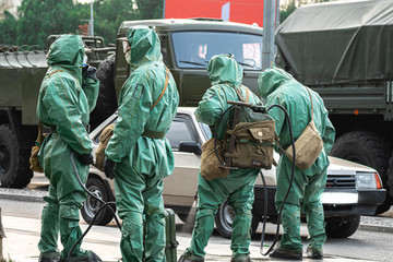 People in bio viral hazard protective suits. Disinfection and decontamination on a public place as...