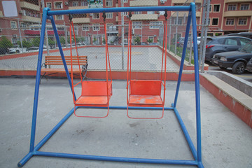 Wooden and Empty red and blue chain swings in children playground . chain swings hanging in garden . Childs swing in a park .