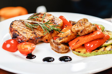 Succulent juicy portion of hot salad with grilled fillet steaks served with tomatoes, ruccola and roast vegetables on white plate. Haute cuisine concept in restaurant