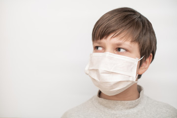 Boy close-up in a medical mask on a white background. The concept of protection, coronavirus and quarantine. Copy space.