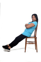 Fototapeta na wymiar portrait of a woman sitting and relaxing on a chair in white background, looking at camera and arms crossed