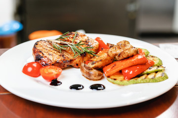 Succulent juicy portion of hot salad with grilled fillet steaks served with tomatoes, ruccola and roast vegetables on white plate. Haute cuisine concept in restaurant