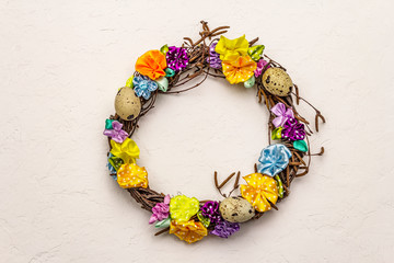 Hand crafted Easter wicker wreath with quail eggs and handmade flowers. Birch branches, polka dot satin ribbon. Stay at home concept. Festive Easter background