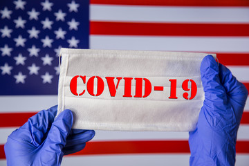Coronavirus outbreak. Coronavirus update in USA. Word Covid-19 on medical mask with flag of United States on background. Spread of corona virus in world. Wuhan virus. Stay at home during quarantine. 