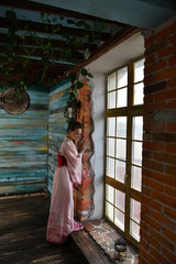 beautiful girl in a pink kimono by the window