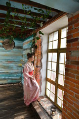 beautiful girl in a pink kimono by the window
