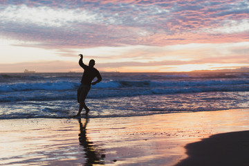 Chico joven haciendo disfrutando de la playa al atardecer