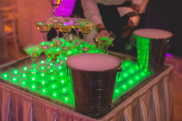 Glasses with alcoholic beverages in the pyramid, beautiful pyramid line of different colored alcohol cocktails with champagne on a wedding party, catering banquet table