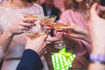 Glasses with alcoholic beverages in the pyramid, beautiful pyramid line of different colored alcohol cocktails with champagne on a wedding party, catering banquet table