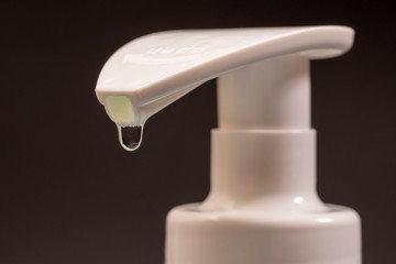 White dispenser for antibacterial soap from which soap is dripping