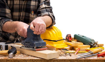 Close-up. Carpenter with the electric sander smoothes a wooden board. Construction industry....
