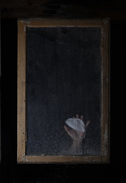 The hand of a person with mask sliding down window frame during the corona virus covis19 pandemic
