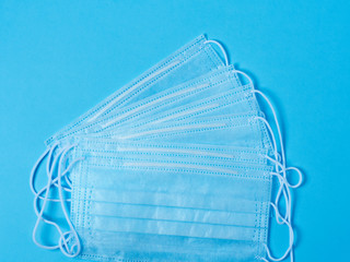 Surgical protective face masks are laid out on a blue background. Concept of protection against viruses and bacteria.