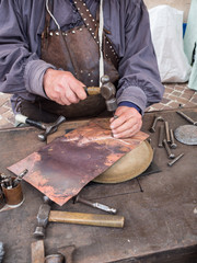 Detail of a craftsman engraves a copper plate with a hammer and chisel. - 333268498
