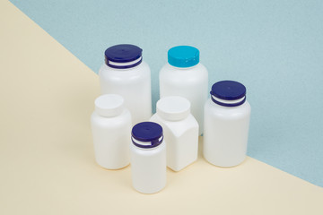 Set of White plastics medicals containers for tablets or capsules on a yellow-blue background