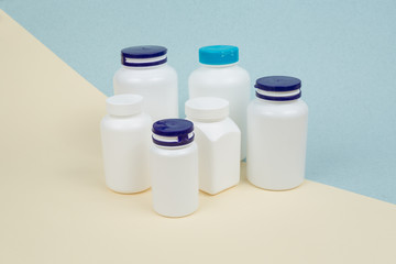 Set of White plastics medicals containers for tablets or capsules on a yellow-blue background