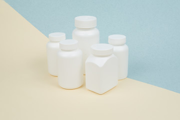 Set of White plastics medicals containers for tablets or capsules on a yellow-blue background
