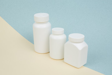 Set of White plastics medicals containers for tablets or capsules on a yellow-blue background