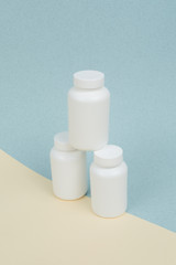 Set of White plastics medicals containers for tablets or capsules on a yellow-blue background
