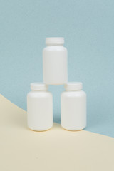 Set of White plastics medicals containers for tablets or capsules on a yellow-blue background