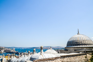 Obraz premium View of Istanbul with the Bosphorus Strait and Galata Bridge through the domes and chimneys of the Suleymaniye Mosque, Turkey 