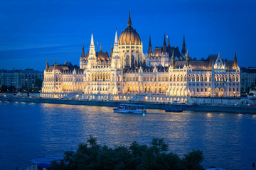 The Budapest Parliament at blue hour. Boats passing by on Danube river, Hungary 2019