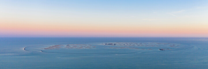 Aerial view of The World Islands on Dubai sea with sunset sky, United Arab Emirates or UAE. Architecture landscape background with sky.