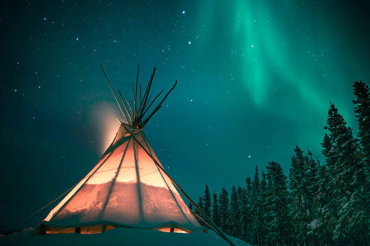 Glowing tipi / teepee in the snowy forest under the northern lights, Yellowknife, Northwest Territories, Canada